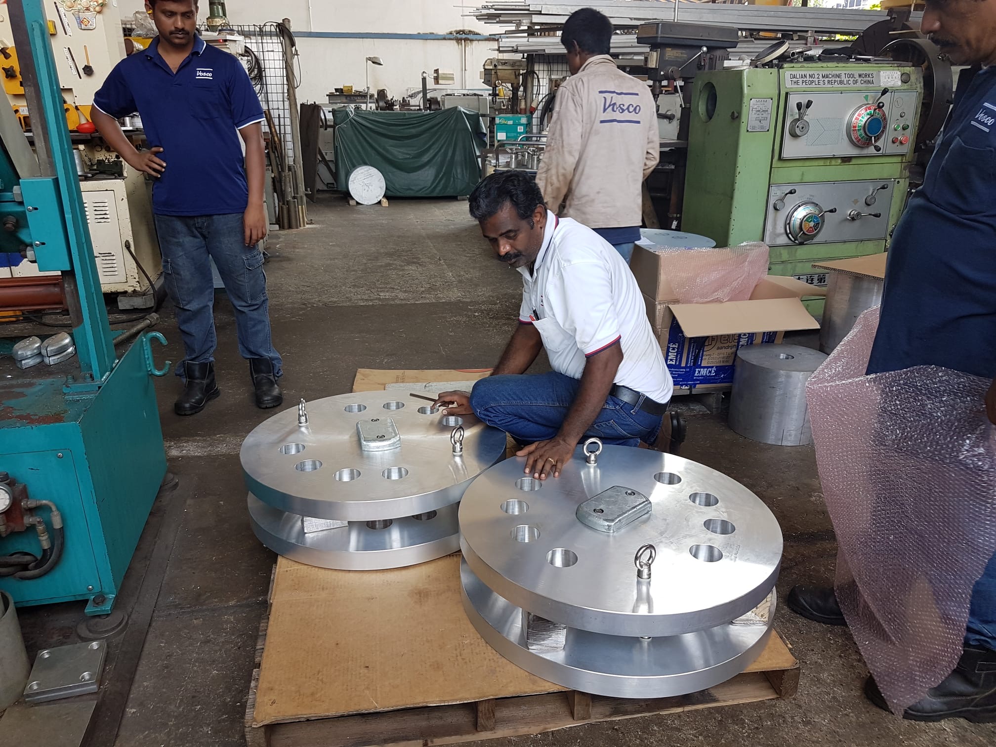 Vosco team gathered around large machined circular components in the workshop